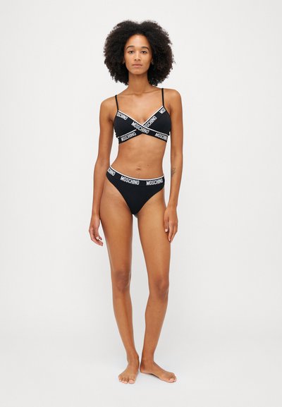 Sort bikini med en bralette og højtaljede underdele, begge med kontrasterende hvide Moschino-logoer. Blødt stof, minimalistisk design.