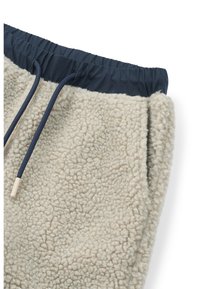 Világos bézs színű, textúrált felületű polár joggers, sötétkék elasztikus derékpánttal és zsinórral. Oldalsó zsebekkel rendelkezik.