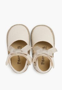Zapatos de tela beige con una superficie de lienzo texturizada, punta redonda y suela de yute trenzado. Presenta un detalle de lazo en cada tira para un ajuste seguro.