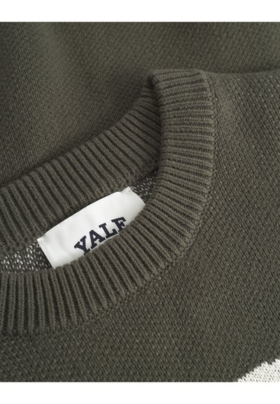 Pull en maille vert foncé avec un col rond côtelé. L'étiquette à l'intérieur indique "YALE." Le tissu semble doux avec une texture subtile.