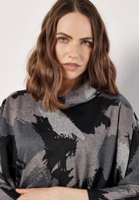 Overmaatse trui met kraag in grijs- en zwarttonen, met een gedurfde abstracte print en een zachte, gestructureerde stof.