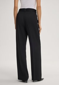Zwarte wijde pijpen broek met een gestructureerde tailleband en riemlussen, van gladde stof en met een op maat gemaakte pasvorm, die een strakke silhouette toont.