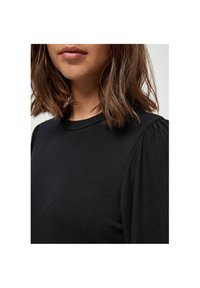Sort ribbet top med rund hals og puffede skuldre. Stoffet har en struktureret overflade, der fremhæver den tætsiddende pasform.
