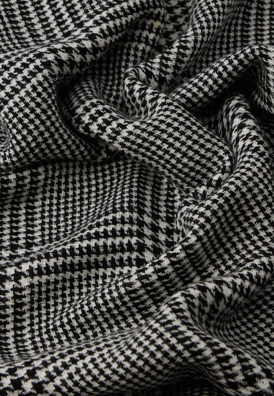 Fekete-fehér mintás szövet, texturált szövettel, amelyen különböző méretű houndstooth és kockás minták találhatók, mélységet és kontrasztot teremtve.