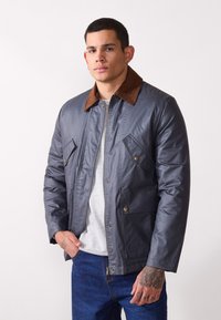 Gray, water-resistant jacket with a brown corduroy collar, zip fastening, and buttoned chest pockets; smooth texture and casual design.