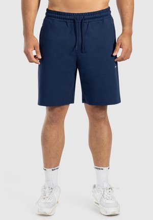 Shorts de sport bleu marine en tissu doux, dotés d'une taille élastique et d'un cordon de serrage. Ils atteignent au-dessus du genou avec une coupe décontractée.