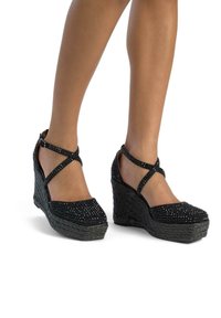 Sandali con tacco a cuneo neri con base in juta intrecciata, decorati con strass e con fasce incrociate alla caviglia per una vestibilità sicura.