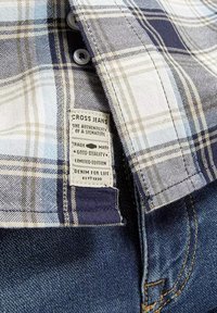 Koszula w kratę w niebieskie, białe i beżowe wzory, z plastikowymi guzikami i metką "CROSS JEANS" wszytą w denimu.