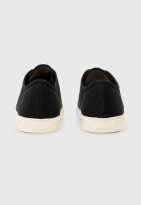 Sneakers neri in tela con punta rotonda, suola in gomma crema a contrasto e dettagli cuciti sul tallone e sul lato.