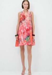 Une robe sans manches avec un motif aquarelle vibrant rose et orange, présentant une silhouette évasée et un tissu doux et léger.