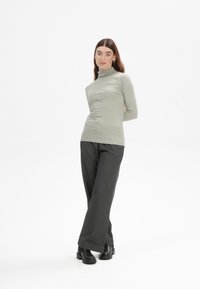 Helles graues Langarm-Turtleneck-Oberteil kombiniert mit weit geschnittenen, anthrazitfarbenen Hosen und schwarzen Knöchelstiefeln, mit einem glatten Stoff und figurschmeichelndem Design.