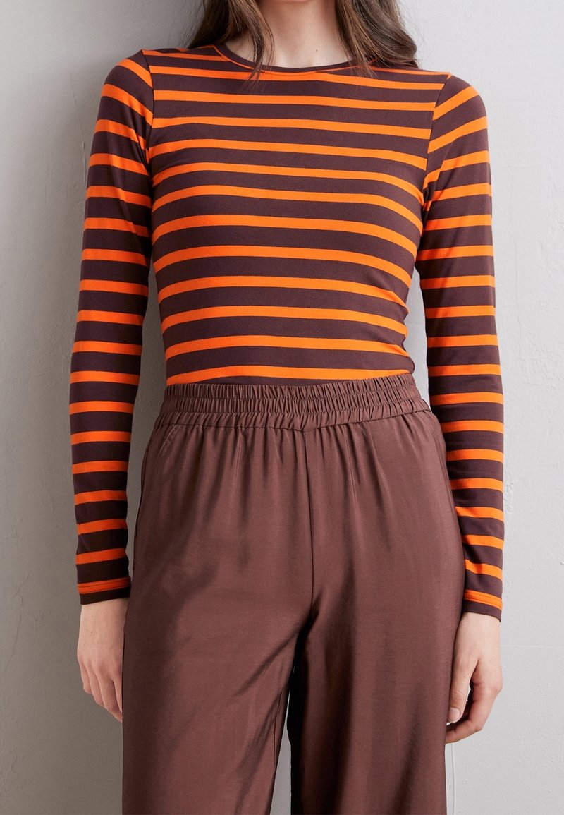 Langarmshirt met horizontale bruine en oranje strepen, gecombineerd met bruine broek met elastische taille, met een relaxte pasvorm en een soepele textuur.