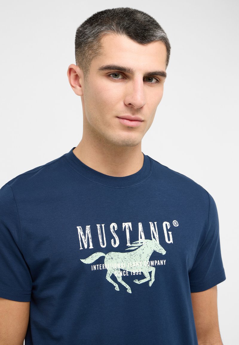 T-shirt en coton bleu marine avec un imprimé graphique blanc d'un cheval et du texte, encolure ronde, manches courtes et coupe décontractée.