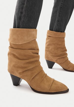 Rjavi semiš gležnarji z zbledele zasnovo in koničastim prstom, z črnim petom in teksturiranimi gubami vzdolž gredi.