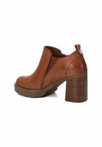 Brązowy skórzany botek sięgający kostki na blokowym obcasie, z bocznym zamkiem błyskawicznym, gumową podeszwą i gładką fakturą. Minimalistyczny design bez wzorów.