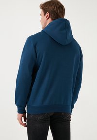 Dunkelblauer Hoodie mit einer Kängurutasche und verstellbarem Kapuzenzug; mit gerippten Bündchen und Saum, glatter Textur und lässiger Passform.
