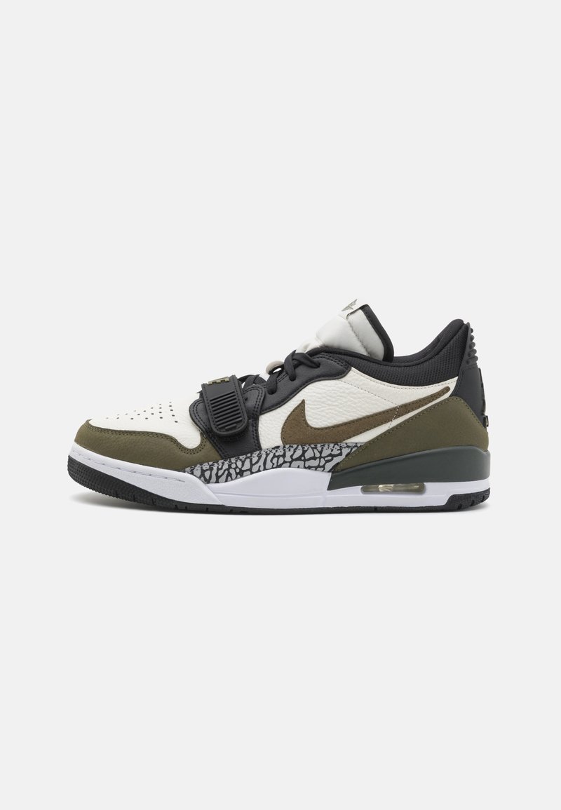 Nike sportcipők, amelyek fehér bőrből készültek, olívazöld részletekkel és egyedi fekete textúrázott középtalppal rendelkeznek.