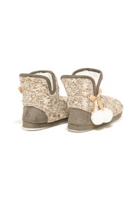 Botines de punto con una textura beige tejida, acentos de ante gris y pompones blancos y esponjosos. Suela flexible para mayor comodidad.