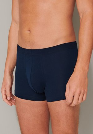 Boxers en coton bleu marine avec un design ajusté, une taille élastique et une poche à l'avant. Texture lisse avec des détails de couture minimaux.