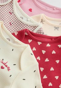 En stapel av fem randiga baby bodysuits med rund halsringning, prydda med mönster av hjärtan, rosetter, körsbär och text i rosa, rött och krämfärgat.