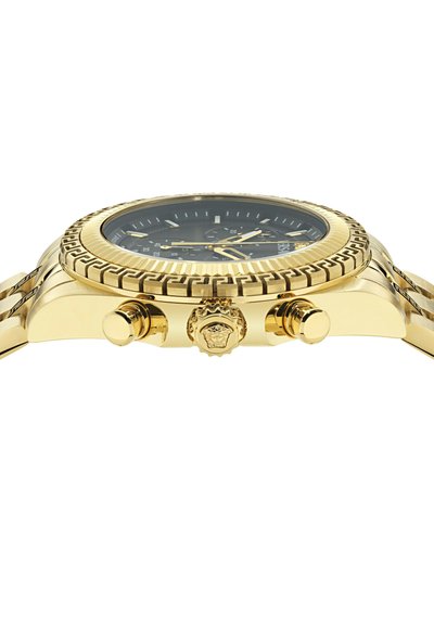 Guld armbåndsur med sort urskive, tre sideknapper og en detaljeret struktureret bezel, vist fra en lav sidevinkel på hvid baggrund.