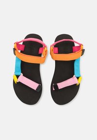 Fargerike sandaler med svarte såler og justerbare stropper i rosa, oransje, blå og gul. Designet inkluderer flere festepunkter.