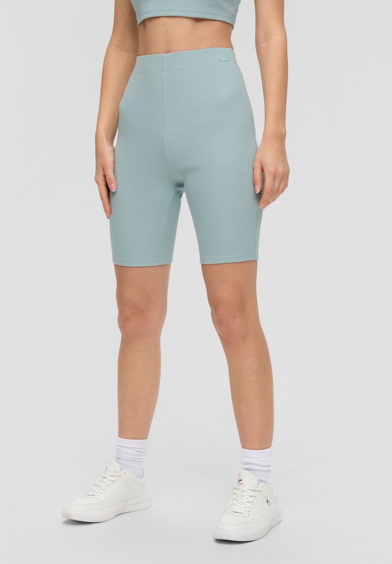 Lichtblauwe geribbelde fietsbroek met hoge taille; gladde textuur; strakke pasvorm; gecombineerd met witte sneakers en crew sokken.