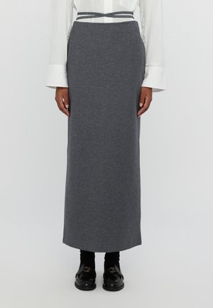 Falda gris hasta la rodilla hecha de una tela suave, con una cintura ajustada y un cinturón texturizado. Combinada con mocasines negros y calcetines negros.