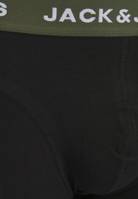 Black cotton boxer briefs with a wide olive green elastic waistband featuring white text. Smooth texture and fitted shape.