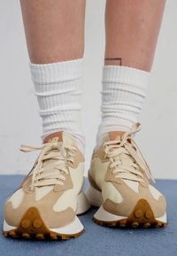 Beige og kremfargede sneakers med semsket skinn og glatt skinn, med runde snører og en teksturert gummisåle. Båret med hvite ribbestrikkede sokker.