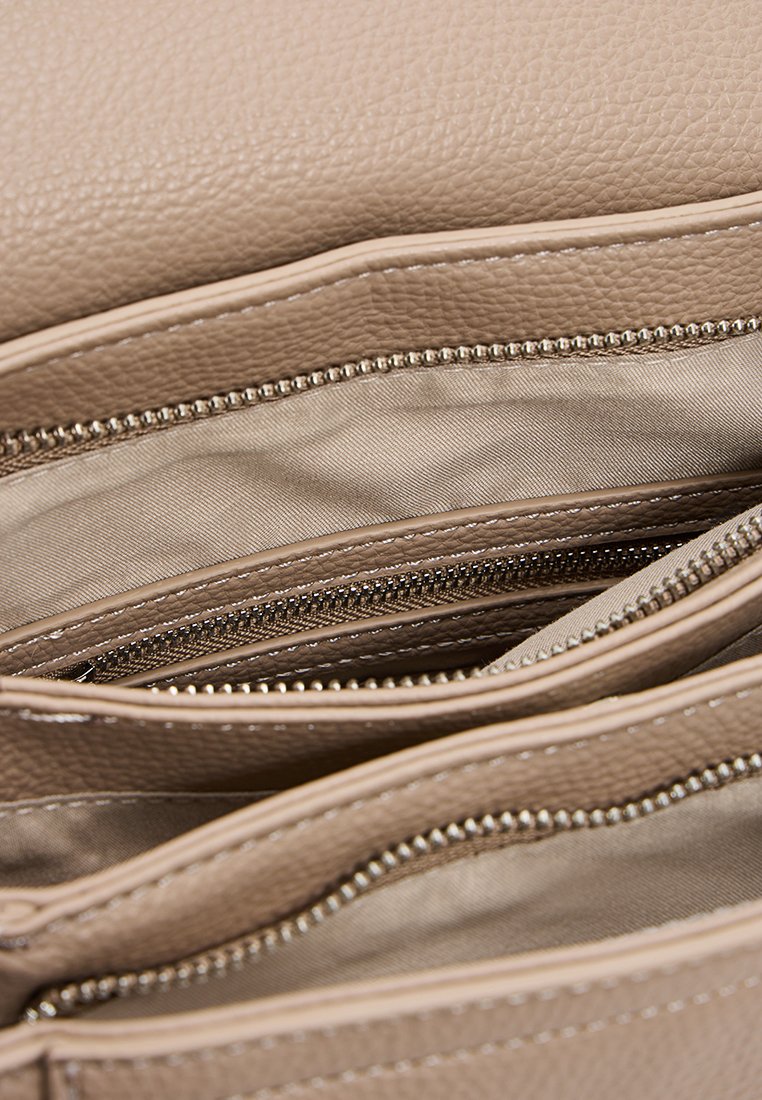 Interno di una borsa a tracolla in pelle beige con molteplici scomparti con zip e foderatura in tessuto morbido, che mette in risalto le caratteristiche organizzative e la texture.