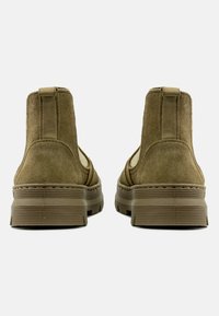 Stivaletti alla caviglia in suede marrone con una finitura testurizzata e suola spessa. Presentano una linguetta sul retro e pannelli laterali di colore chiaro a contrasto.
