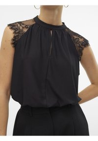 Blouse noire sans manches avec un col haut, présentant des accents en dentelle sur les épaules et un détail en forme de trou à l'avant. Texture lisse.