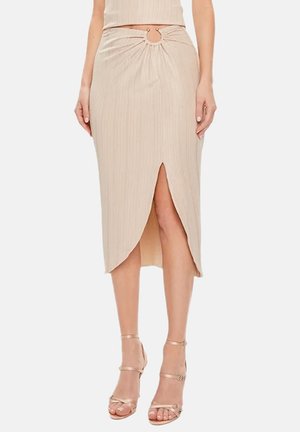Gonna midi beige a coste con spacco frontale e taglio circolare in vita, indossata con sandali beige con tacco alto e cinturini su una modella.