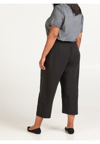 Svarta korta byxor gjorda av ett lätt tyg med resår i midjan. Tillsammans med en mörkgrå t-shirt med kort ärm.