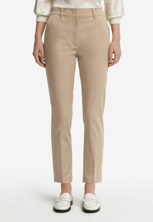 Beige skräddarsydda byxor med smal passform, med sidofickor, en mjuk tygstruktur och minimalistisk design. Bärs med vita loafers.
