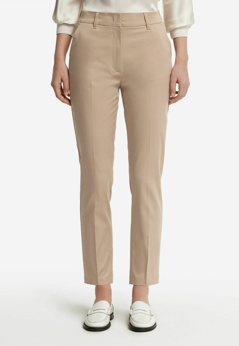 Beige skräddarsydda byxor med smal passform, med sidofickor, en mjuk tygstruktur och minimalistisk design. Bärs med vita loafers.