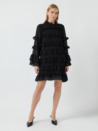 Μαύρο φόρεμα με ρέλια και μακριά μανίκια, που διαθέτει στρώσεις φρουφρού. Διαφανές ύφασμα προσθέτει υφή; ο σχεδιασμός είναι άνετος.