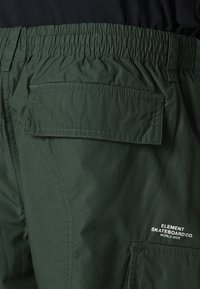 Grønne cargo shorts laget av lett materiale, med elastisk midje, baklomme og hvite logo detaljer.