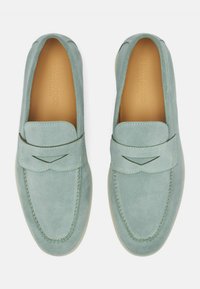 Lys grønne ruskinds loafers med en sømdesignet og rund tå. Har en dekorativ rem med udskæring. Glat indvendig foring.
