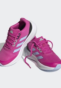 Scarpe da ginnastica rosa con una parte superiore in rete testurizzata, caratterizzate da tre strisce azzurro chiaro, accenti grigi e suola bianca. Inclusi i lacci.