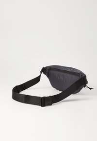 Grau Nylon Hüfttasche mit gebogener Form, schwarzem verstellbarem Gurt, Reißverschlussverschluss und minimalem Branding auf der Vorderseite.