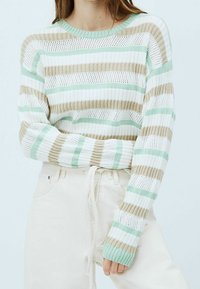 Stribet striktrøje i hvid, mintgrøn og beige. Har ribbede kanter ved hals og ærmer, med en løs pasform og åben strikketekstur.