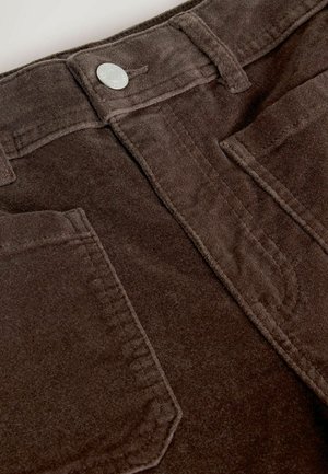 Braune Cordhosen mit strukturierter Oberfläche, Fünf-Taschen-Design und einem silbernen Knopfdetail am Bund.