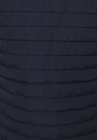 Marineblauwe gewatteerde pufferjack met horizontale naden, een gladde textuur en een lichtgewicht, geïsoleerd ontwerp.