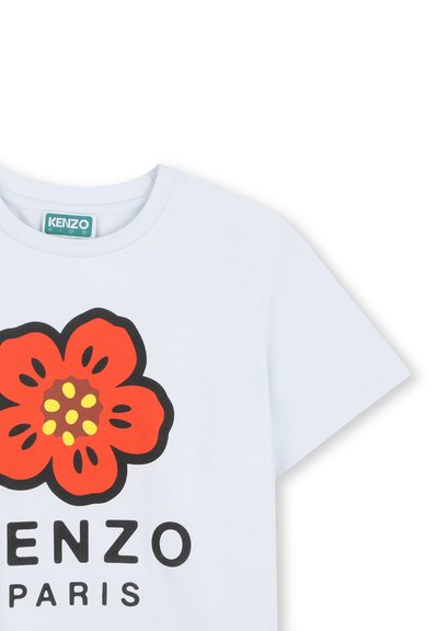 T-shirt en coton blanc avec un grand motif floral rouge comportant des détails jaunes et marron. "KENZO" et "PARIS" imprimés en noir en dessous.