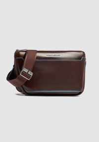 Borsa a tracolla in pelle marrone con dettagli blu, chiusura con zip e tracolla regolabile. Presenta una forma rettangolare elegante e una texture liscia.