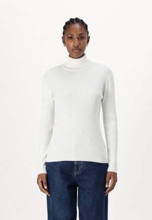 White ribbed turtleneck sweater with long sleeves, featuring a slim fit and soft texture paired with blue wide-leg jeans.