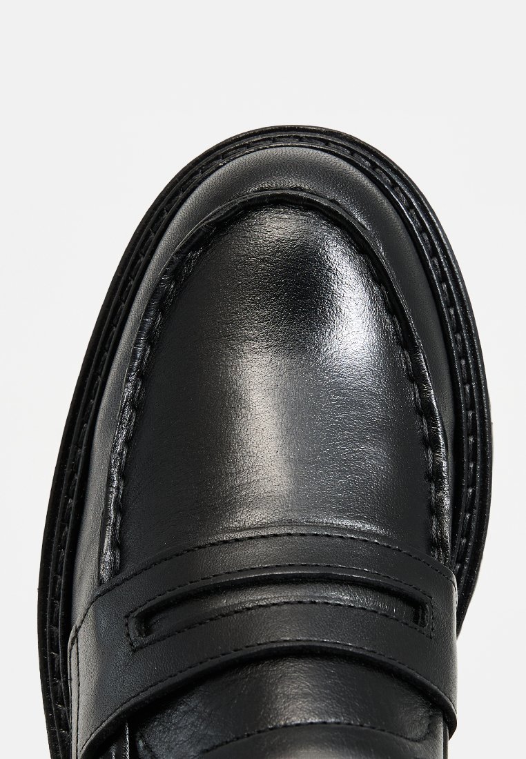 Schwarze Lederloafers mit einer glatten Textur, gesteppten Details und einem erhöhten Band über dem Obermaterial. Das Design ist elegant und minimalistisch.