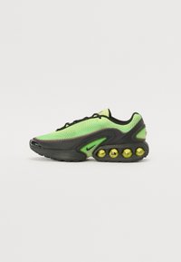 Nike sneakers featuring a mesh upper in bright green, black accents, and a distinctive sole with visible yellow air bubbles.